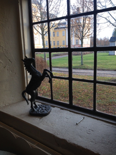 Fotot visar ett fönster med galler och en staty av en häst.