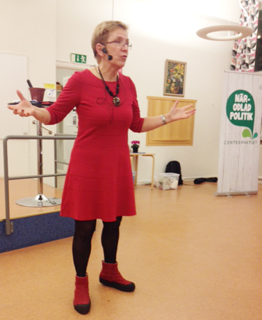 Kerstin Lundgren, kvinna i rös klänning gestikulerar med armarna, när hon talar vid Centerpartiets årsmöte i Katrineholm.